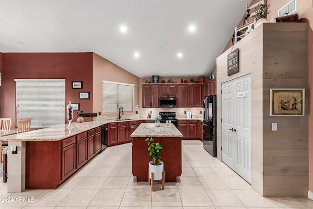 kitchen featuring black appliances, lofted ceiling, a kitchen island, and a kitchen breakfast bar