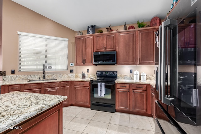 kitchen with light tile patterned floors, black appliances, sink, light stone countertops, and lofted ceiling