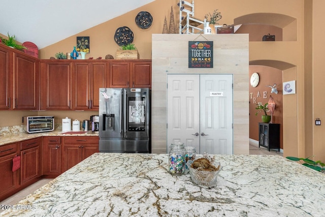 kitchen featuring stainless steel refrigerator with ice dispenser, high vaulted ceiling, and light stone countertops