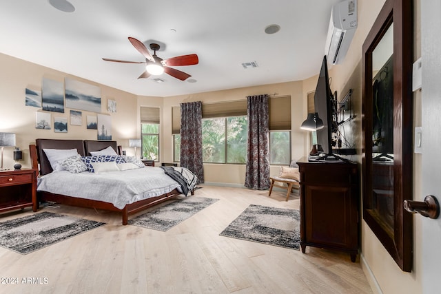 bedroom with ceiling fan, an AC wall unit, and light hardwood / wood-style floors