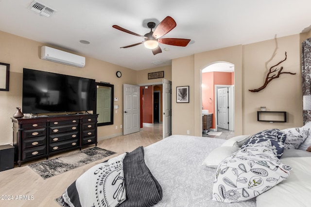 bedroom with light hardwood / wood-style flooring, ceiling fan, a wall mounted air conditioner, and ensuite bathroom