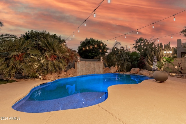 pool at dusk with a patio area