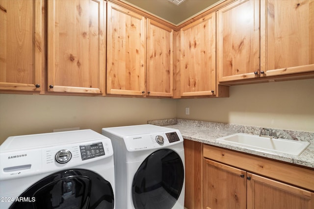 clothes washing area featuring cabinets, separate washer and dryer, and sink