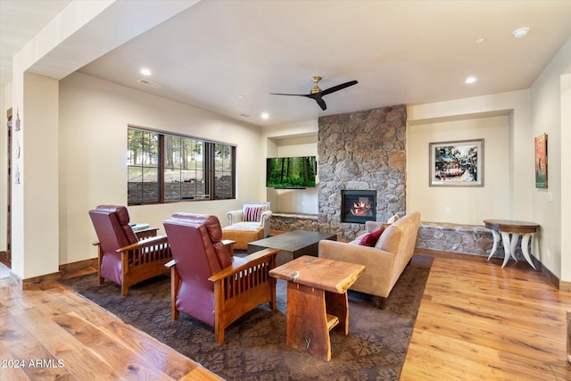 living room with a stone fireplace, ceiling fan, and hardwood / wood-style floors