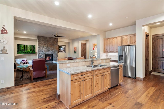 kitchen featuring sink, an island with sink, wood-type flooring, and appliances with stainless steel finishes