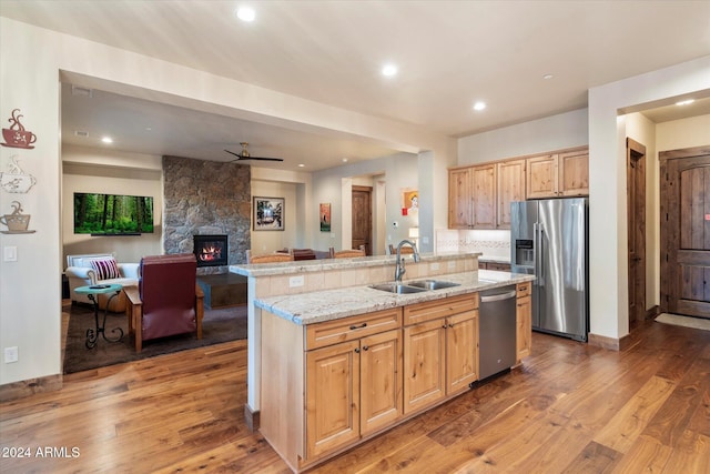 4320 W Arabian Trl, Flagstaff, AZ 86005 - kitchen with appliances with stainless steel finishes, a sink, a fireplace, open floor plan, and light wood-type flooring