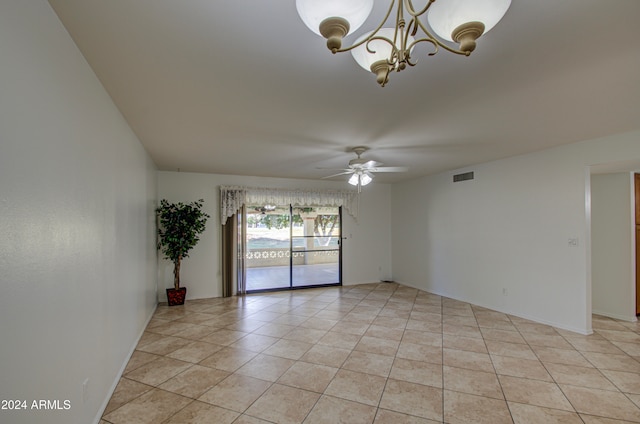 tiled spare room with ceiling fan with notable chandelier