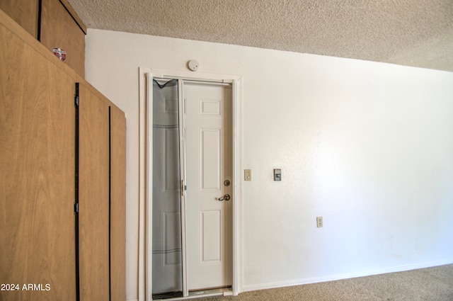 hall with light colored carpet and a textured ceiling