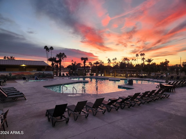 pool at dusk featuring a patio area