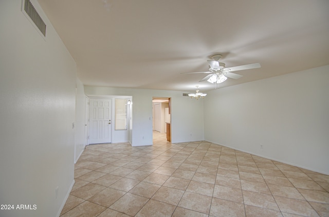 spare room with ceiling fan with notable chandelier and light tile patterned flooring