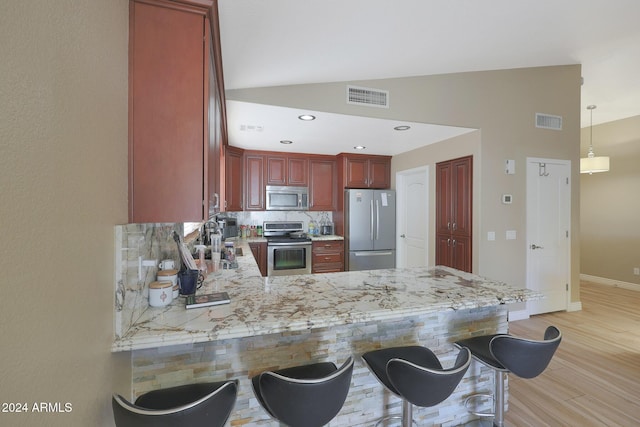 kitchen featuring hanging light fixtures, backsplash, kitchen peninsula, lofted ceiling, and appliances with stainless steel finishes