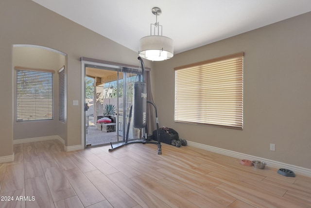 workout area featuring vaulted ceiling and light hardwood / wood-style flooring