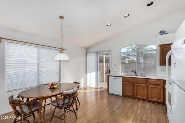 dining room featuring lofted ceiling, sink, and light hardwood / wood-style floors