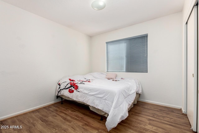 bedroom with dark hardwood / wood-style flooring and a closet