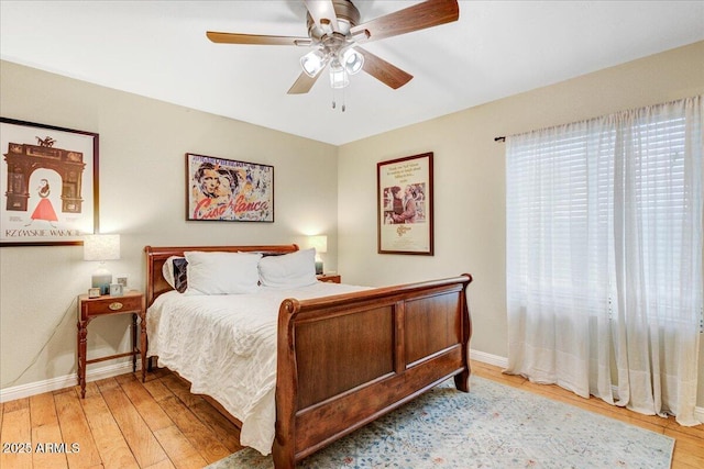 bedroom featuring ceiling fan, light wood-style flooring, and baseboards