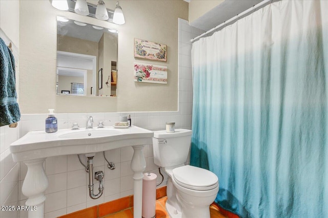 bathroom with toilet, a wainscoted wall, tile walls, and a shower with shower curtain