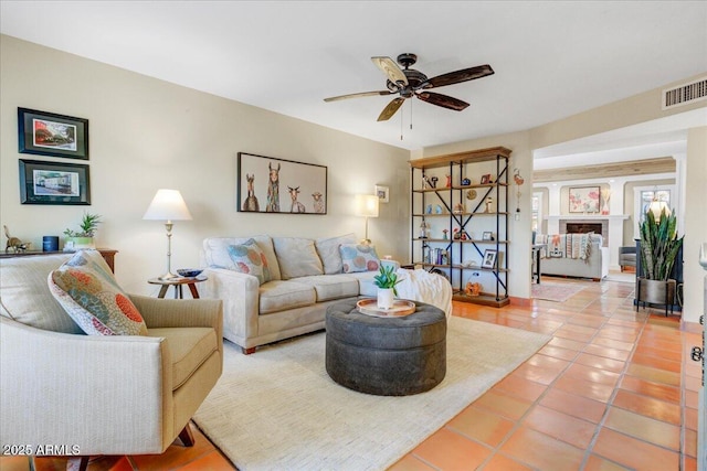 living room with light tile patterned flooring, visible vents, and a ceiling fan