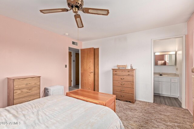 bedroom with a sink, carpet flooring, ensuite bath, and a ceiling fan