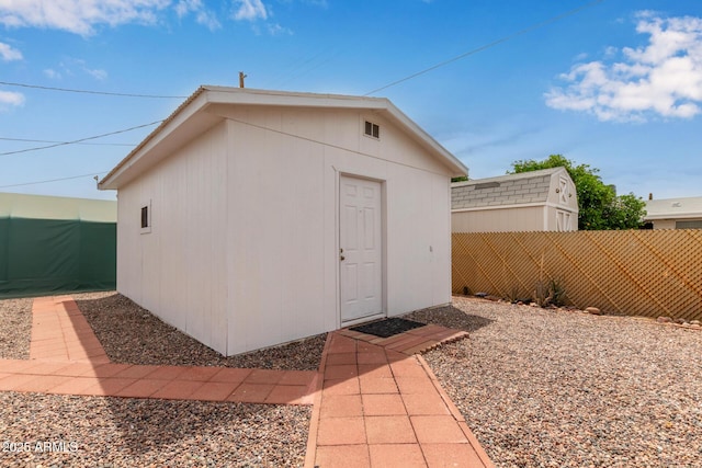 view of outbuilding featuring fence and an outbuilding