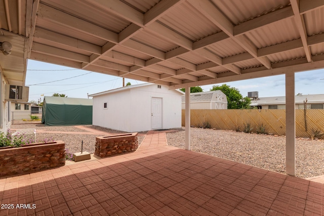 view of patio featuring fence, an outbuilding, and a storage unit