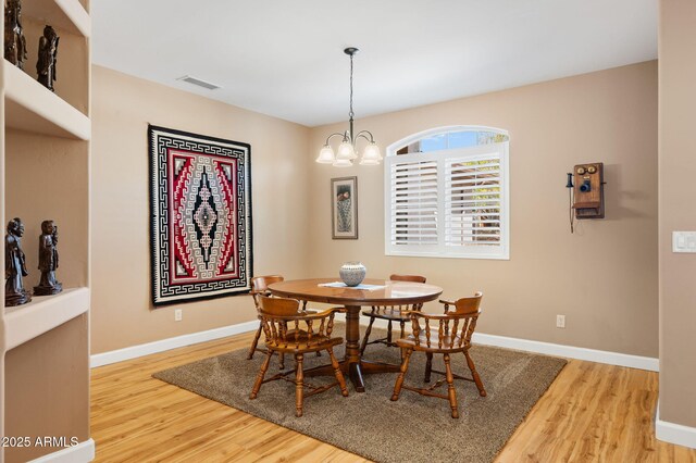 dining area with visible vents, baseboards, wood finished floors, and a chandelier