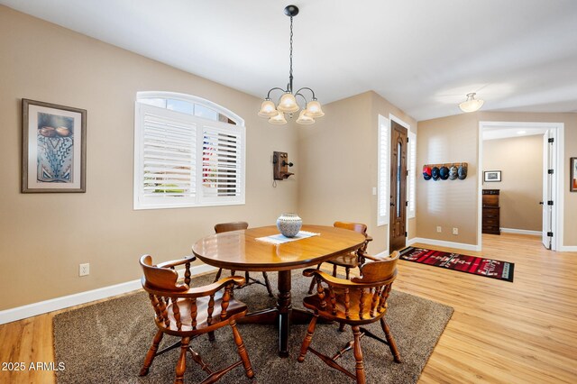 dining area featuring an inviting chandelier, baseboards, and wood finished floors