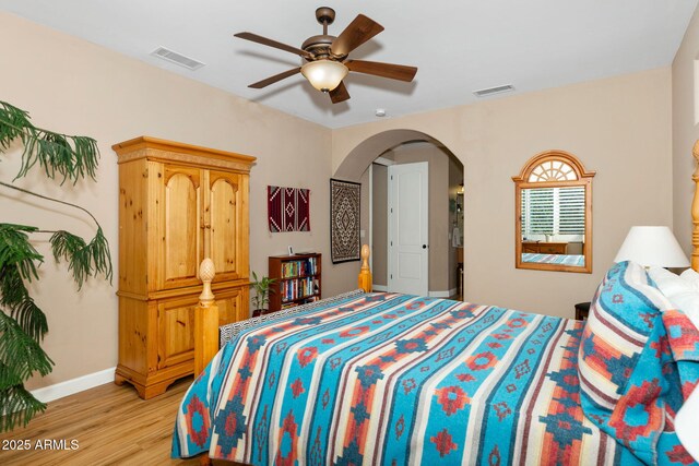 bedroom with arched walkways, baseboards, visible vents, and light wood finished floors