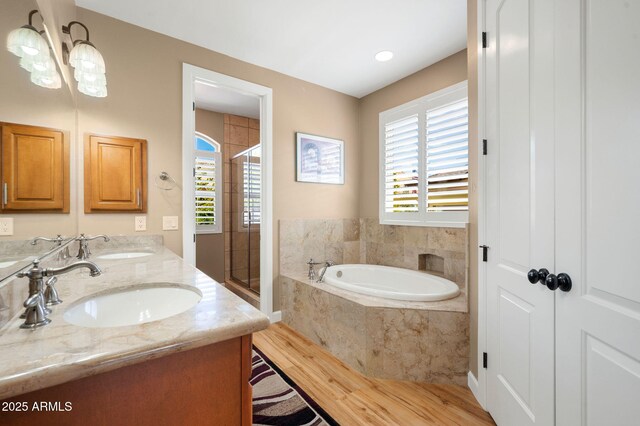 full bathroom with a sink, double vanity, wood finished floors, a garden tub, and a stall shower