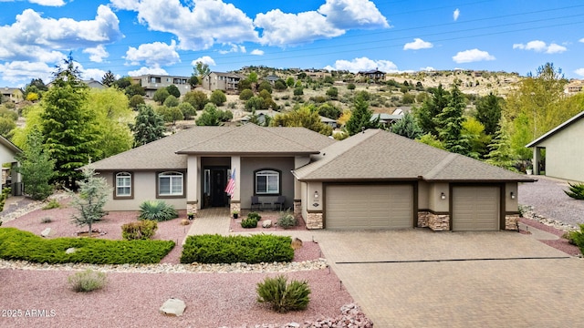 view of front of home with an attached garage, decorative driveway, stucco siding, and stone siding