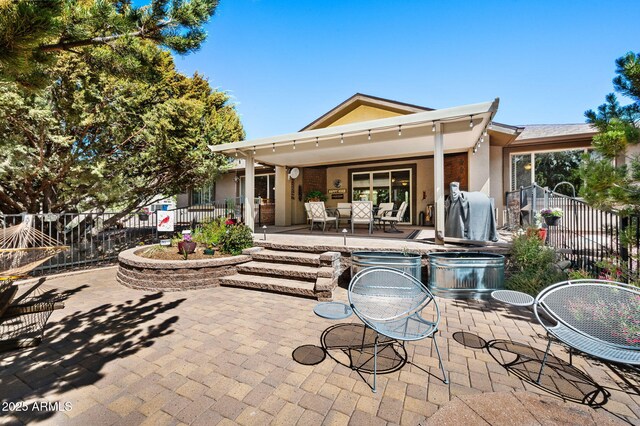 rear view of property featuring a patio, fence, and stucco siding