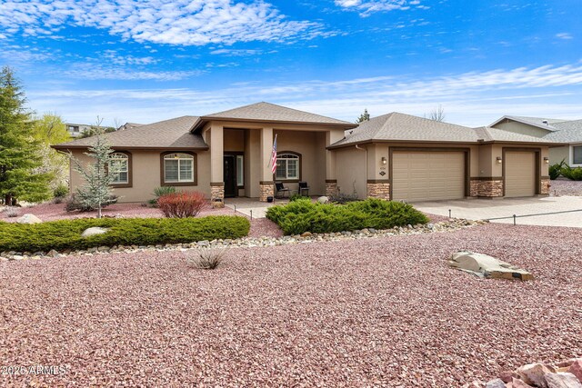 prairie-style home featuring an attached garage, driveway, stucco siding, and stone siding