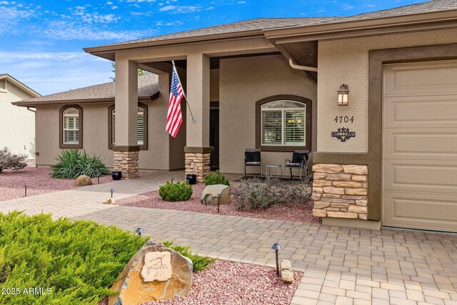 view of exterior entry with stucco siding, covered porch, and stone siding