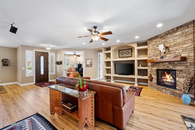 living area with baseboards, ceiling fan, a fireplace, and wood finished floors