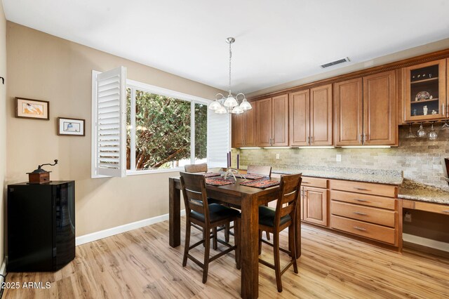 dining room featuring a notable chandelier, baseboards, visible vents, and light wood-style flooring