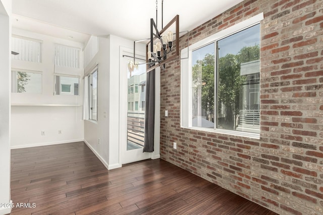3633 N 3rd Ave Unit 2031, Phoenix, AZ 85013 - unfurnished dining area with a chandelier, dark wood-style flooring, and brick wall