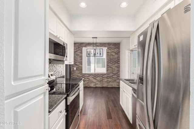 3633 N 3rd Ave Unit 2031, Phoenix, AZ 85013 - kitchen featuring stainless steel appliances, white cabinetry, dark wood-type flooring, brick wall, and pendant lighting
