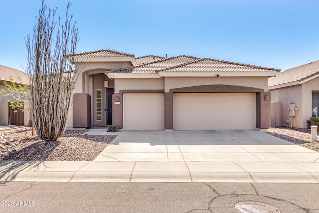 mediterranean / spanish house featuring a garage, concrete driveway, a tile roof, and stucco siding