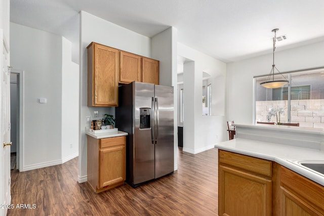 kitchen with brown cabinetry, visible vents, stainless steel refrigerator with ice dispenser, and dark wood-type flooring