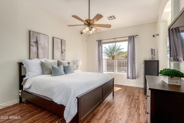 bedroom with a ceiling fan, wood finished floors, visible vents, and baseboards