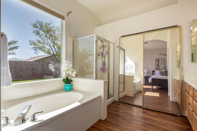 full bath featuring wood finished floors, a shower stall, vanity, ensuite bath, and a bath