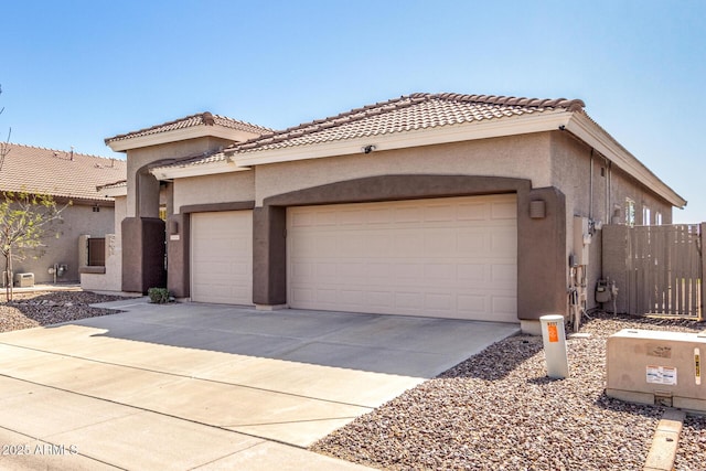 mediterranean / spanish-style home with a tile roof, stucco siding, fence, a garage, and driveway