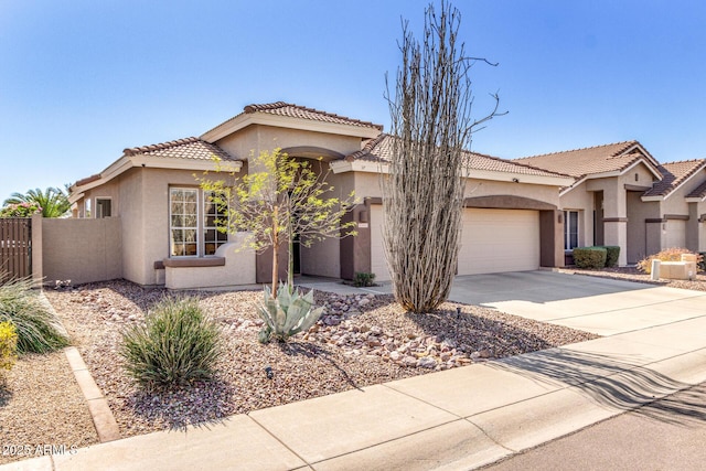 mediterranean / spanish-style home featuring an attached garage, fence, concrete driveway, a tiled roof, and stucco siding