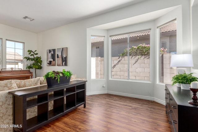 living area with dark wood finished floors, visible vents, and baseboards