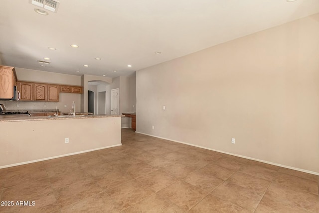 kitchen featuring arched walkways, recessed lighting, a sink, visible vents, and baseboards