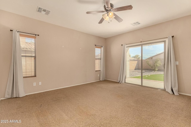 carpeted empty room featuring a ceiling fan, visible vents, and baseboards