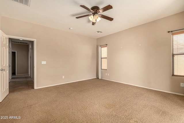 carpeted spare room featuring baseboards, visible vents, and a ceiling fan