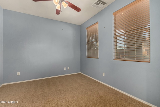 carpeted spare room with a ceiling fan, visible vents, and baseboards