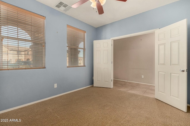 unfurnished bedroom featuring light carpet, multiple windows, visible vents, and baseboards