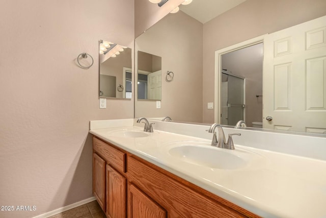 bathroom featuring double vanity, a sink, toilet, and tile patterned floors