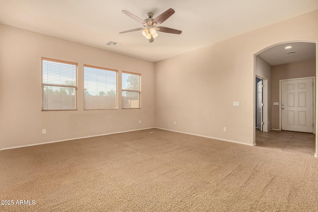 unfurnished room featuring arched walkways, visible vents, light carpet, ceiling fan, and baseboards